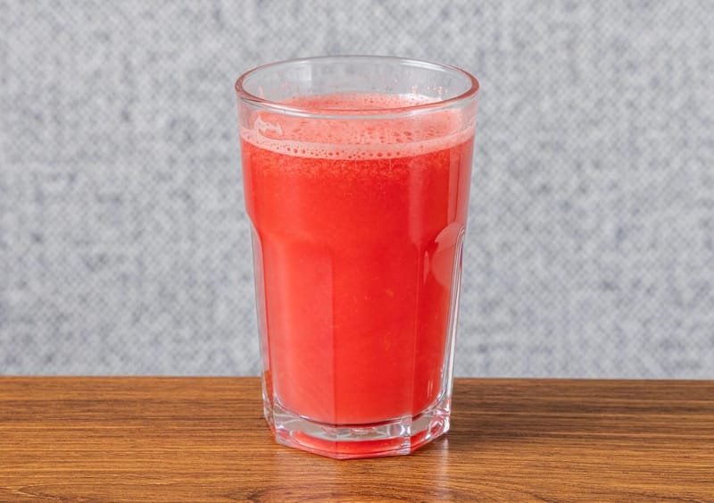A tall glass of fresh watermelon juice on a wooden table