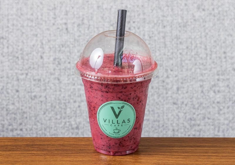 Berry Mix smoothie, bright magenta, in a Villas Cafe takeaway cup with a black straw